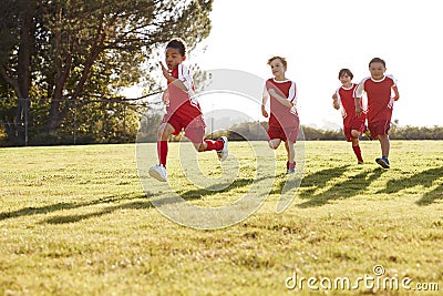 Four young boys in football strip running in a playing field Stock Photo