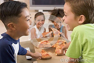 Four young children indoors eating pizza Stock Photo