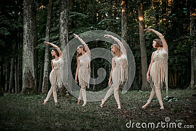 Four young female dancers dance synchronously in the forest barefoot. Stock Photo