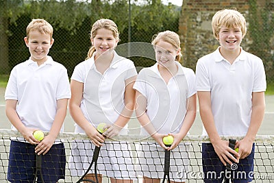 Four young friends on tennis court smiling Stock Photo