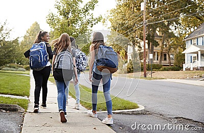 Four young teen girls walking to school together, back view Stock Photo