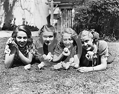 Four young women lying outside with baby chicks. Stock Photo