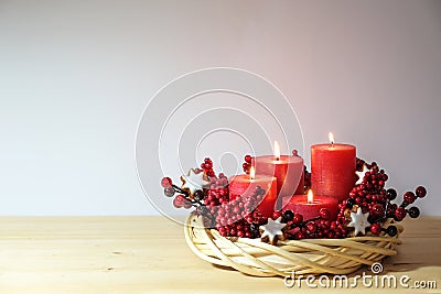 Fourth advent with four lit red candles in a natural willow wicker wreath with cinnamon star cookies and artificial berries, Stock Photo