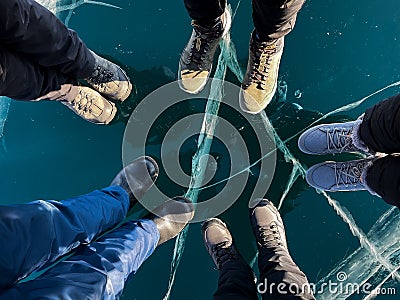 Fragile thin brittle ice underfoot. Male and female feet on ice. Cracks on ice background. Ice of Lake Baikal Stock Photo