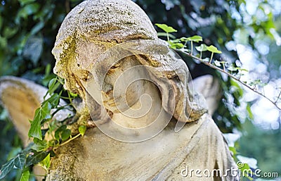 A fragment of ancient sculpture angel in a golden glow in the old cemetery. Stock Photo