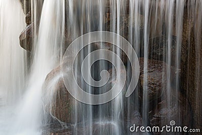 fragment of a beautiful waterfall with large stones with vertical blurry streams and splashes. close-up side view Stock Photo