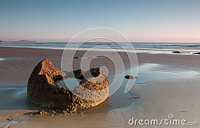 Fragment of a boulder on the ocean shore at sunrise Stock Photo