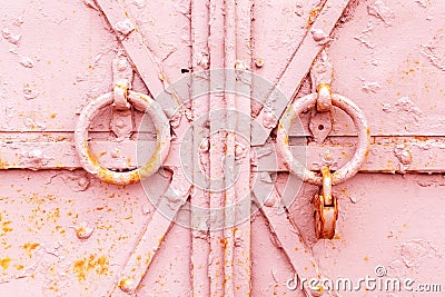 Fragment of a closed old metal door or gate with round knockers and a rusty padlock. Closeup shabby worn texture of iron Stock Photo