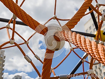 Fragment of cobweb in the playground. Detail of cross orange ropes in safety climbing outdoor equipment. Stock Photo