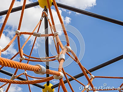 Fragment of cobweb in the playground. Detail of cross orange ropes in safety climbing outdoor equipment. Stock Photo