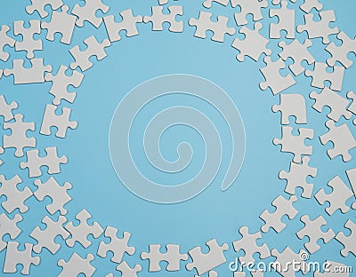 Fragment of a folded white jigsaw puzzle and a pile of uncombed puzzle elements against the background of a blue surface Stock Photo