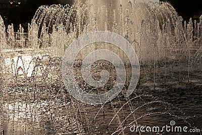 Fragment of fountain at sunset in sepia colors. Beautiful silvery streams of water sparkle in the sun. Atmospheric evening city Stock Photo