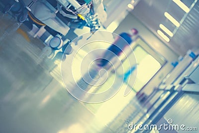 Fragment of the hospital corridor with a silhouette of a worker, the patient`s bed and the reflection of light from the floor, Stock Photo