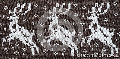 Fragment of a knitted fabric of handkerchief hand-knitted brown wool. Figure winter Christmas theme. White deer. View from above. Stock Photo
