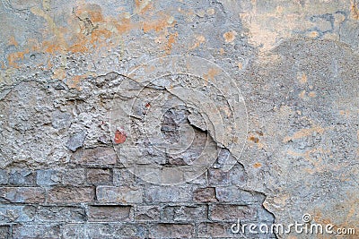 Fragment of old brick wall with partially collapsed cracked gray cement plaster, brickwork is visible where is facing damage Stock Photo