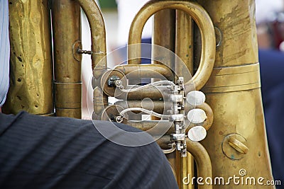 A fragment of an old musical instrument tuba, standing between the legs of a tired street musician Stock Photo