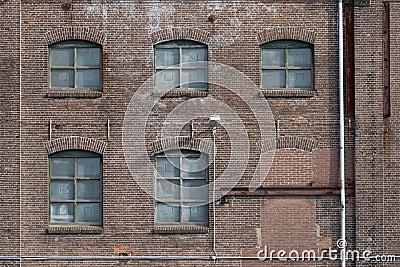 A fragment of an old and weathered facade of an old factory, made of masonry, steel and wooden frames Stock Photo