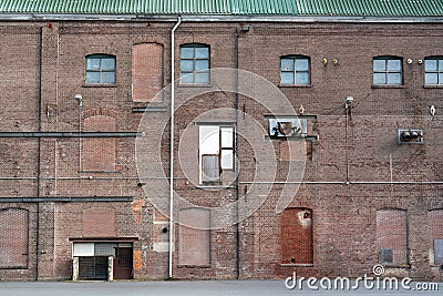 A fragment of an old and weathered facade of an old factory, made of masonry, steel and wooden frames Stock Photo