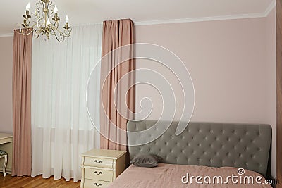 fragment of pink bedroom with curtain, tulle, bed, pillow and nightstand closeup photo Stock Photo