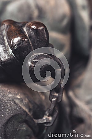 fragment sculpture an iron hand squeezes chain Stock Photo