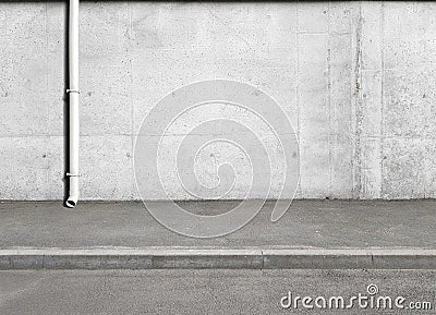 A fragment of a street city concrete wall of a building, a rain facade pipe or a rain shower on the facade and an asphalt pavement Stock Photo