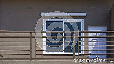 Fragment of white wooden door and glass window on brown cement wall with balcony on external view of house building, exterior Stock Photo