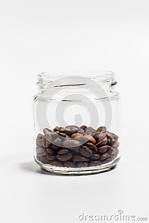 Fragrant coffee grains in a small glass jar on a white background Stock Photo