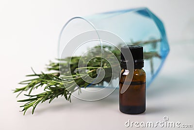 fragrant medicinal evergreen rosemary on a light background with a transparent glass and a jar of hair oil. medical Stock Photo
