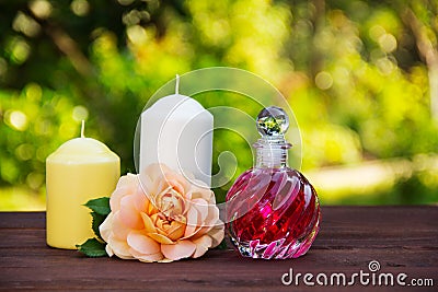 Fragrant rose oil in a beautiful glass bottle. Pink elixir, candles and flowers. Spa concept. Romantic concept. Stock Photo