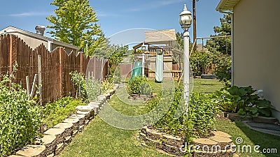 Frame Garden with lush plants and childrens playground under blue sky on a sunny day Stock Photo