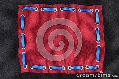 Frame made of blue ribbon inserted into a red fabric. Stock Photo