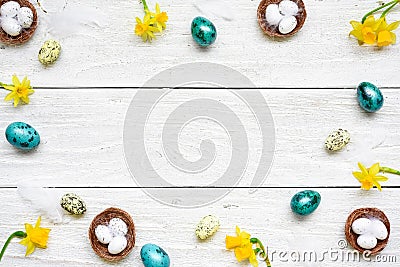 Frame made of easter eggs, spring flowers and feathers on white wooden background. easter composition Stock Photo