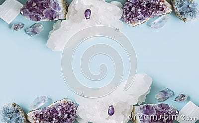 Frame made out of and raw natural crystal geode clusters, amethyst, celestite, quartz on light blue background for copy space. Stock Photo