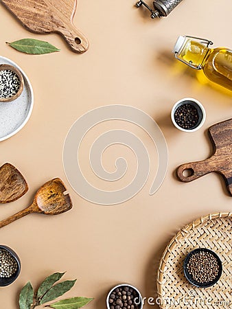 Frame of small bowls various dry spices, wood kitchen utensils, olive oil in glass bottle on beige background. Top view. copy Stock Photo