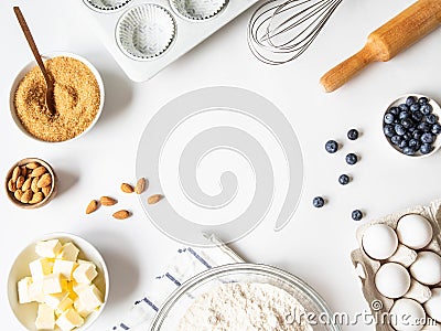 Frame of various baking ingredients - flour, eggs, sugar, butter, fresh blueberries, nuts, kitchen utensils and cupcake baking Stock Photo