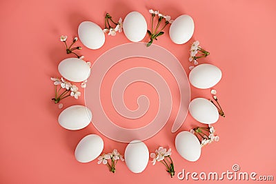 A frame of white flowers and white eggs on a pink background. Copy space, top view. Easter background. Stock Photo