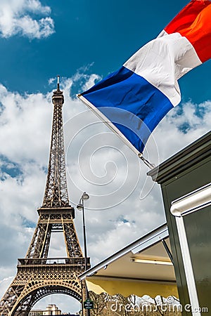 France flag over blue cloudy sky and Eiffel tower in Paris Stock Photo