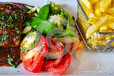 Franch meal with tomato and beans salad, french fries and steak with souse Stock Photo