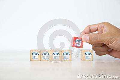 Franchise, Close-up hand choose cube wooden toy block stacked with franchises business store icon for business growth and branch Stock Photo