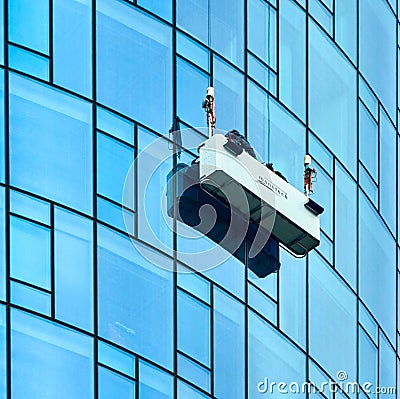 Window cleaners at work in a gondola suspended from steel cables on the facade of the Maintower in Frankfurt Editorial Stock Photo