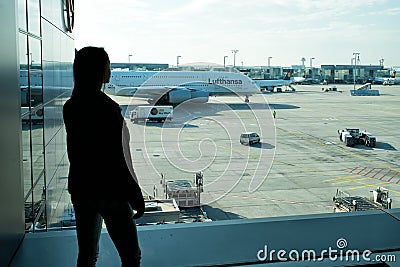 Frankfurt am Main, Germany - October 11, 2015: girl silhouette look at planes on airdrome ground on sunny day. Woman in airport. T Editorial Stock Photo