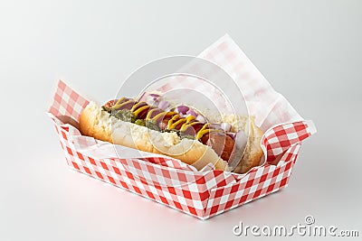 A frankfurter in a disposable checkered tray isolated against a white background. Stock Photo