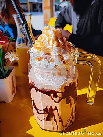 Frappuccino in large glass mug on the table at cafe in a sunny day Stock Photo