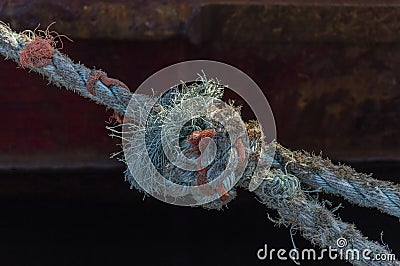 Frayed line securing fishing vessel to wharf Stock Photo