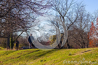 A young caucasian man is walking his dog in the Baker Park, Frederick in autumn in the afternoon Editorial Stock Photo