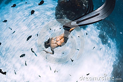 Free diver girl with fins glides over sandy bottom with tropical fishes in blue sea Stock Photo