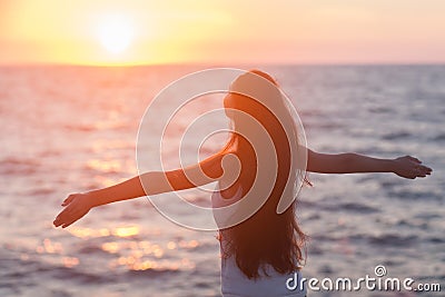 Free woman enjoying freedom feeling happy at beach at sunset. Stock Photo