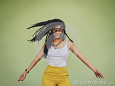 Free your hair and your heart will follow. an attractive young woman dancing against a green background. Stock Photo