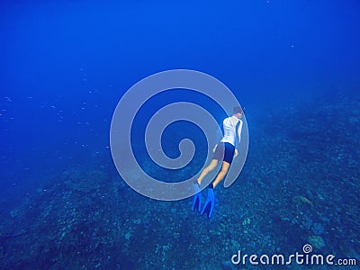 Freediver underwater in deep blue sea. Snorkeling man dives up to water surface. Stock Photo