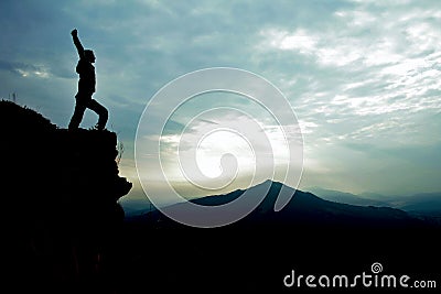 Man on top of cliff with arms raised Stock Photo